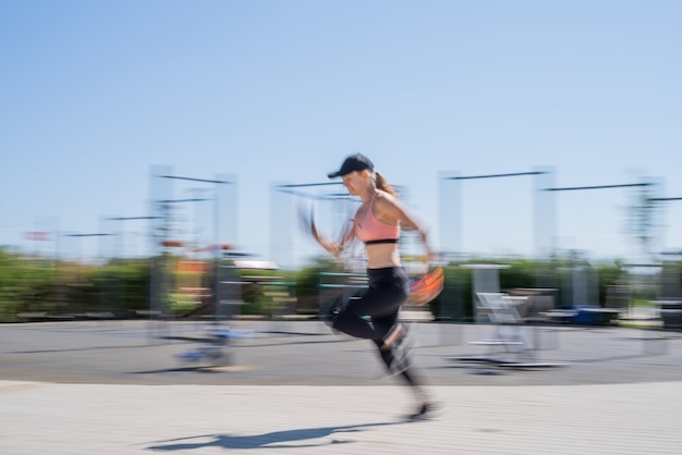 Deportiva mujer trabajando en el campo de deportes en un día soleado de verano