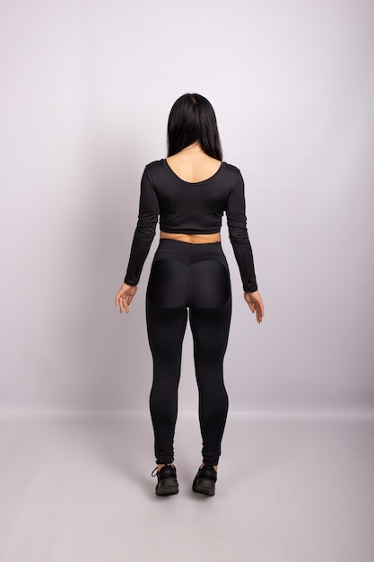 Deportiva mujer vestida con polainas negras y top. Vista trasera