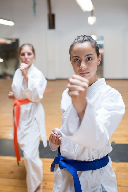 Deportivas mujeres jóvenes en el entrenamiento de karate. Mujeres atractivas en ropa blanca con cinturones azules y rojos calentando antes de entrenar. Deporte, concepto de estilo de vida saludable