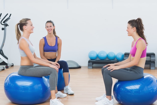 Deportivas mujeres jóvenes sentados en bolas de ejercicio