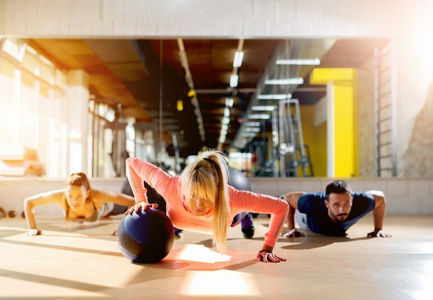 Deportivos jóvenes haciendo flexiones en el gimnasio mirando centrado