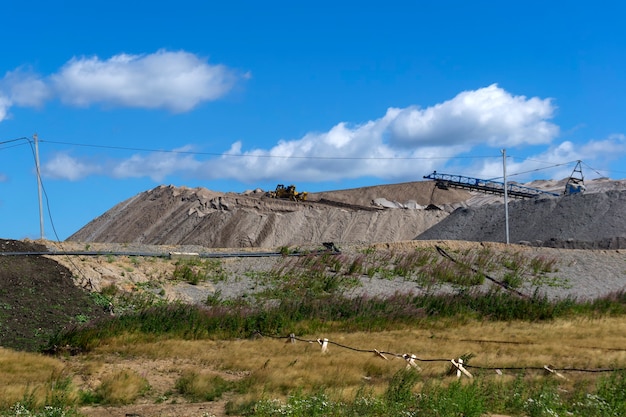 Depósitos de rocha minerada com espalhador e escavadeira de trabalho, vista geral