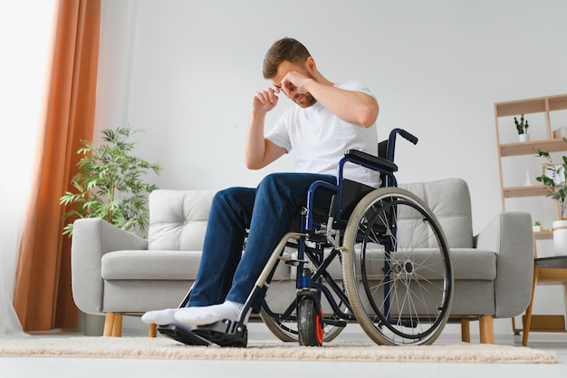Depressão e solidão em homem com deficiência Homem idoso em cadeira de rodas chorando dentro de casa