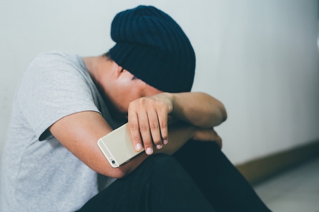 Depressiver Mann, der Smartphone hält