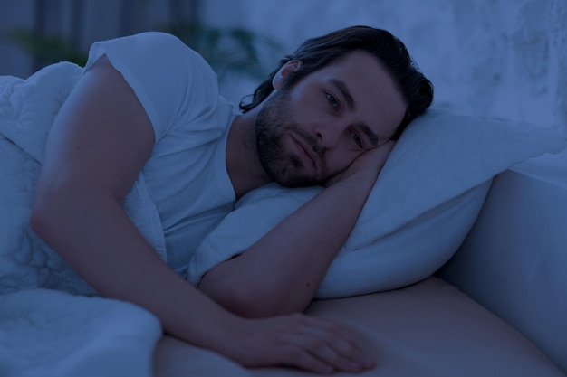 Depressiver Mann kann nachts nicht schlafen, wenn er alleine im Bett liegt