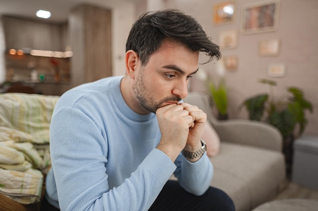 Depressiver Mann sitzt nachdenklich auf der Couch
