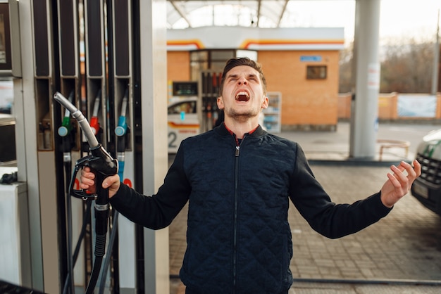 Foto depressiver mann weint auf tankstelle, kraftstofffüllung