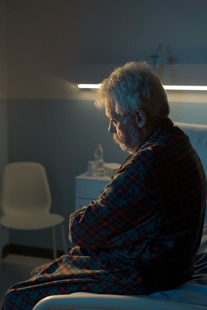 Depressiver Senior, der allein auf dem Krankenhausbett sitzt