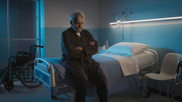 Depressiver Senior, der allein auf dem Krankenhausbett sitzt