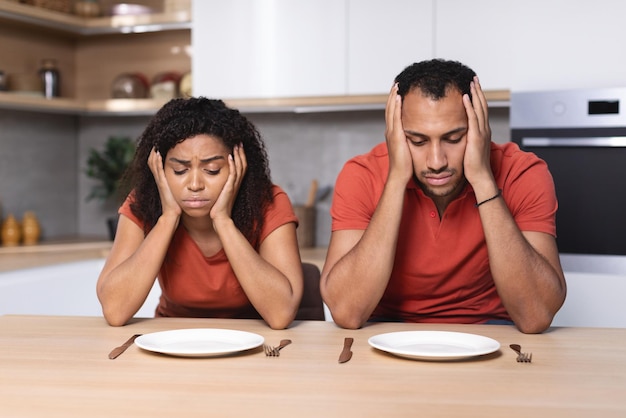 Deprimido, triste, pensativo, milenario, afroamericano, esposa, y, marido, sostener la cabeza, con, manos, mirar, platos vacíos