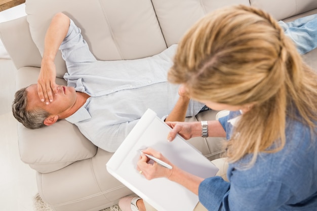 Foto deprimierter mann, der auf couch liegt und mit therapeuten spricht