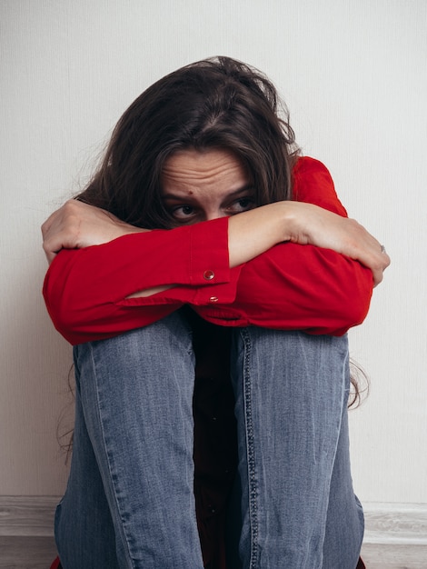 Foto deprimiertes mädchen in einem roten hemd gegen die wand