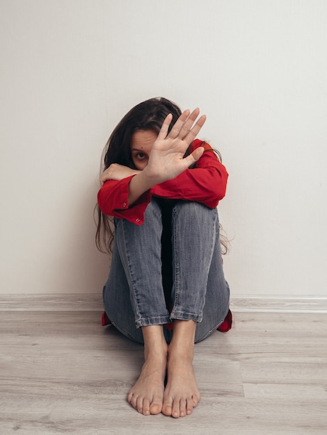 Foto deprimiertes mädchen in einem roten hemd gegen die wand