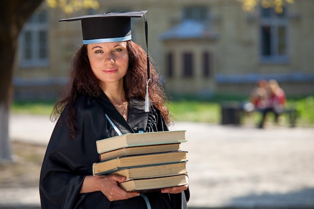 Der Absolvent mit Büchern in einem Universitätshof