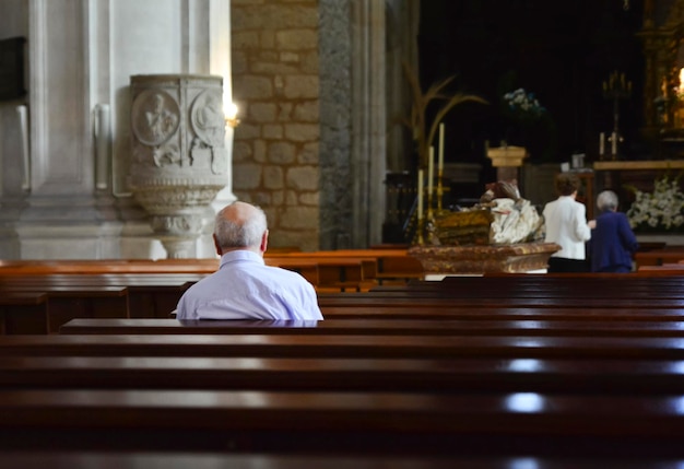 Der ältere Mann betet in einer Kirche