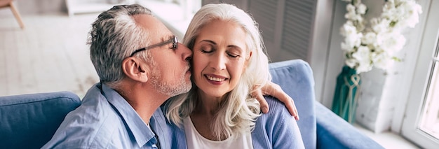 Der ältere Mann und eine Frau mit Blumen küssen sich