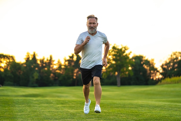 Der ältere Sportler, der auf dem Gras läuft