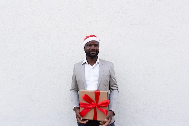 Der Afroamerikaner in der Neujahrsmütze mit einem Geschenk