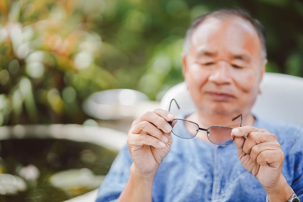 Der alte Mann hielt seine Brille hoch und sah zu, bevor er sie mit einem Lächeln im Gesicht aufsetzte