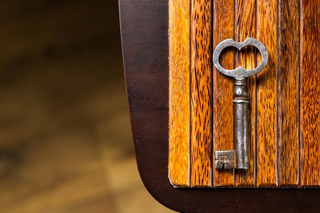 Der alte Schlüssel liegt auf einem alten Holztisch, natürliche Texturen, die das Konzept der Entdeckungsgeheimnisse beantworten