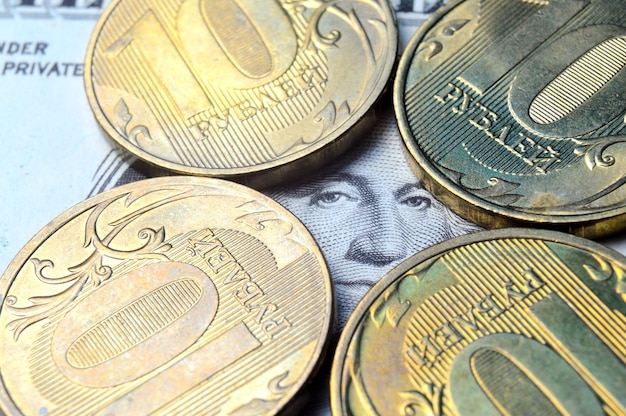 Der amerikanische Dollar, auf dem russische Münzen mit einem Nennwert von 10 Rubel liegen Übersetzung der Inschriften auf den Münzen "10 Rubel", Nahaufnahme