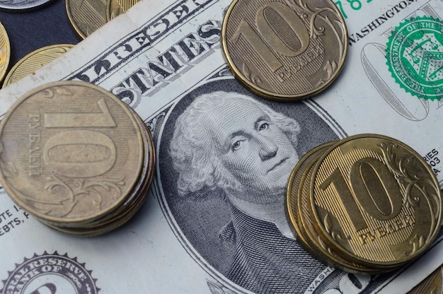 Der amerikanische Dollar, auf dem russische Münzen mit einem Nennwert von 10 Rubel liegen Übersetzung der Inschriften auf den Münzen "10 Rubel", Nahaufnahme