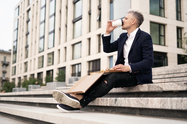 Der Anwalt macht Pause und bestellt Pizza mit Lieferung und Americano-Kaffee Ein Geschäftsmann