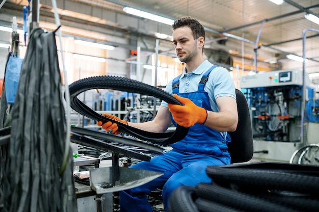 Der Arbeiter an der Montagelinie hält den Fahrradreifen ab Werk. Produktion von Fahrradrädern in der Werkstatt, Installation von Fahrradteilen, moderne Technologie