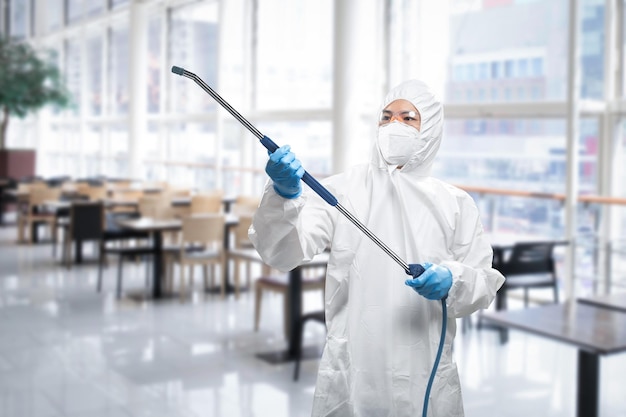 Der Arbeiter trägt einen medizinischen Schutzanzug oder einen Overall, der mit Spray desinfiziert wird