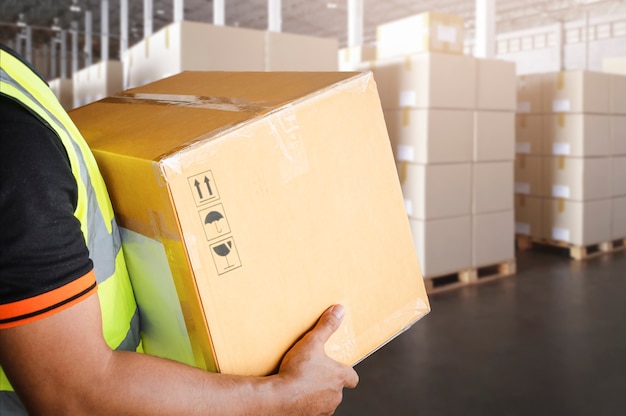 Der Arbeiterkurier trägt eine Paketkiste im Lagerhaus Lieferung Verpackung Versandkartons