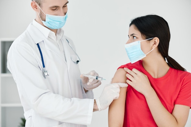 Der Arzt führt mit einem medizinischen Maskenplan eine Injektion in den Arm des Patienten durch. Hochwertiges Foto