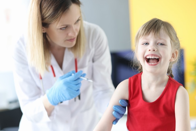 Der Arzt gibt dem kleinen Mädchen eine Injektion bei der Schulterimpfung des Kinderkonzepts