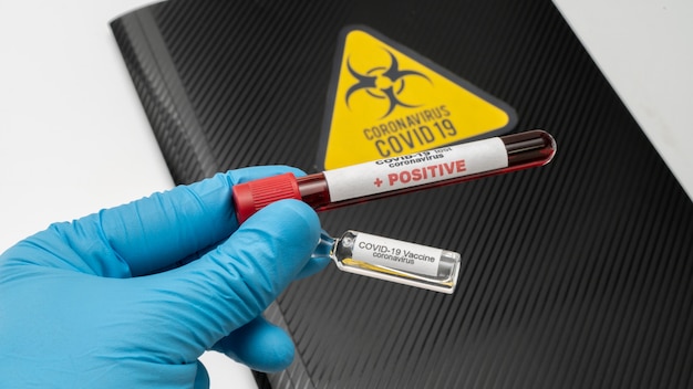 Foto der arzt hält den covid 19 coronavirus-impfstoff in der hand, eine infizierte blutprobe im probenröhrchen. impfstoff zur vorbeugung, immunisierung und behandlung von covid-19