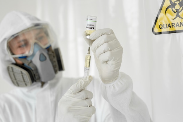Der Arzt hält den COVID 19 Coronavirus-Impfstoff in der Hand. Impfstoff- und Spritzeninjektion Zur Vorbeugung, Immunisierung und Behandlung. In einem sicheren Labor führen Wissenschaftler einen Forschungsimpfstoff durch.