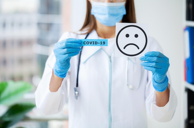 Der Arzt hält eine Karte mit dem Sad-Smile-Symbol im Büro der Klinik