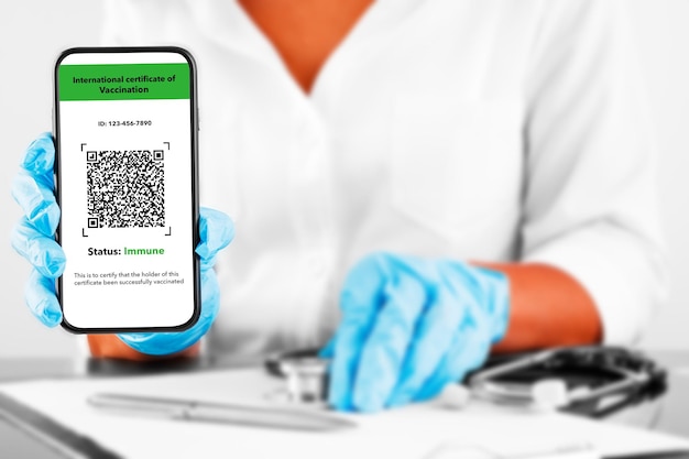 Der arzt hält mit dem handy ein mockup für den digitalen impfpass in der hand