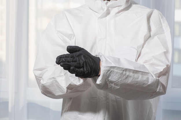 Der Arzt in PSA-Anzuguniform und Handschuhen behandelt die Hände mit einer antiseptischen Nahaufnahme. Coronavirus-Ausbruch. Konzept der Covid-19-Quarantäne. Arzt und medizinische Versorgung. Persönliche Schutzausrüstung Stoppen Sie den Virus.