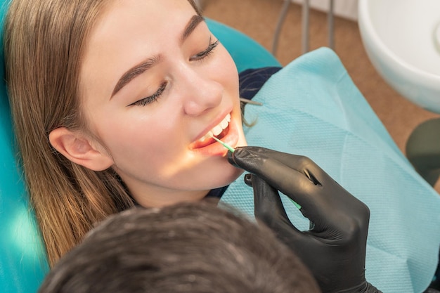 Der Arzt schmiert den Zahn des Patienten während der Behandlung