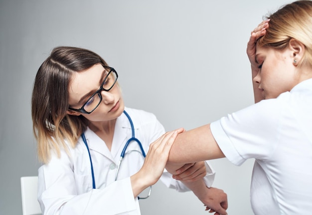 Der Arzt sitzt auf einem Stuhl und die Patientin sitzt drinnen vor einem hellen, beschnittenen Hintergrund