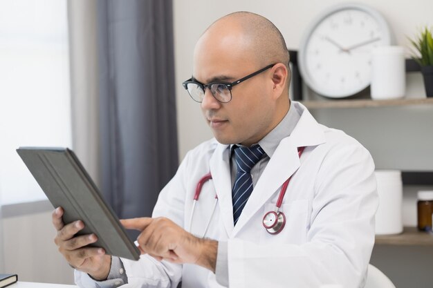 Der Arzt spricht mit dem Patienten über eine Online-Videokonferenz mit Blick auf den Bildschirm. Erklären Sie die Einnahme von Medikamenten zur Behandlung von Krankheiten und notieren Sie den Bericht mit dem Tablet