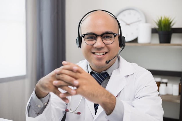 Der Arzt spricht mit dem Patienten über eine Online-Videokonferenz, während er mit einem Headset in die Kamera blickt. Erklären Sie die Einnahme von Medikamenten zur Behandlung von Krankheiten