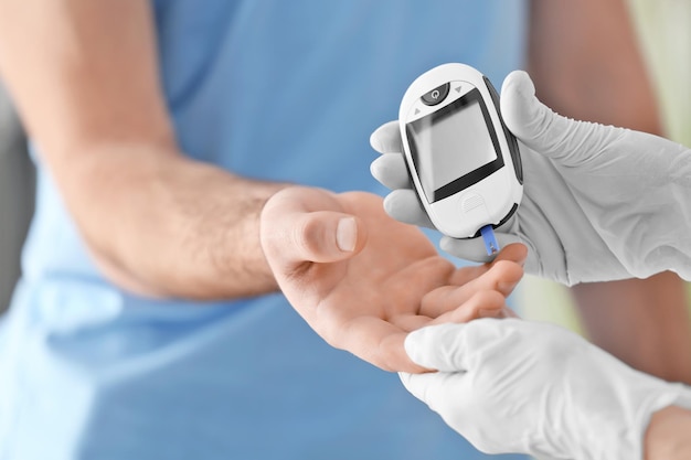 Der Arzt überprüft den Blutzuckerspiegel des Diabetikers mit einem digitalen Glukometer in der Nähe