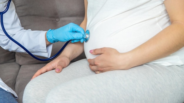 Der Arzt untersucht den Bauch einer schwangeren Frau. Selektiver Fokus