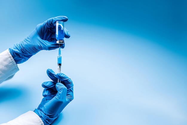 Der Arzt zieht eine Ampulle mit einem Impfstoff daraus in eine Spritze und bereitet eine Injektion oder Impfung vor