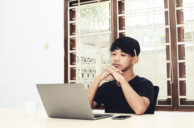 Der Asiate sitzt mit ernster Miene vor dem Laptop