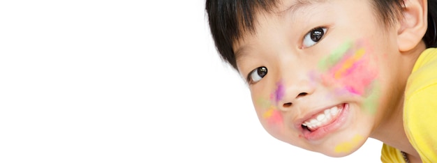 Der asiatische kleine Junge lächelte und hatte einen Aquarellfleck auf seinem Gesicht auf weißem Hintergrund mit Kopierraum