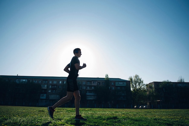 Der Athlet joggt in Kopfhörern auf dem Rasen