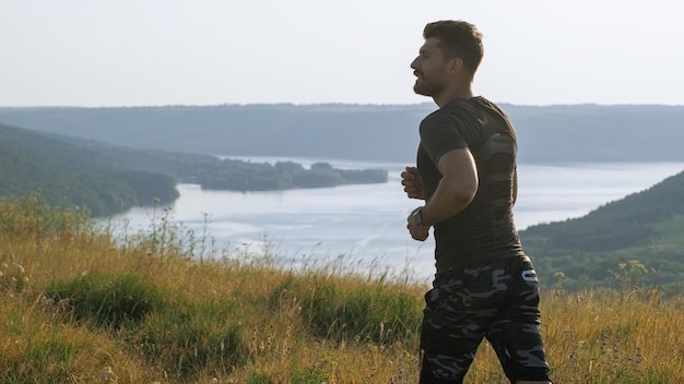 Der attraktive Sportler, der auf dem malerischen Hintergrund joggt