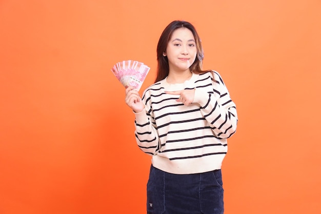 Der Ausdruck einer lächelnden asiatischen Frau, die in der Hand ein paar Rupien Geld für den Einkauf für fa