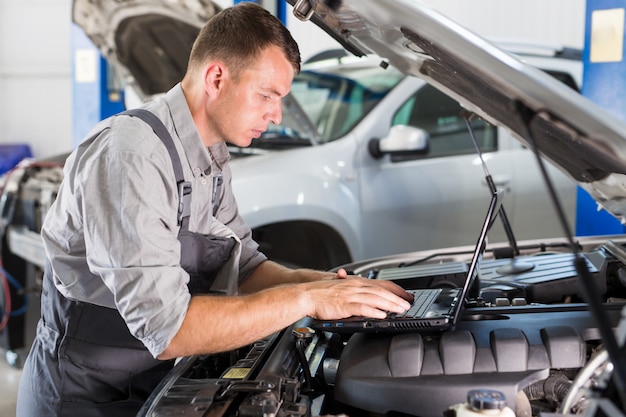 Der Auto-Servicemitarbeiter führt Diagnosen und Autoreparaturen im Raum durch.